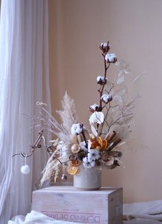 a vase filled with lots of flowers on top of a wooden box next to a window