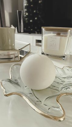 an egg sitting on top of a glass plate next to a candle and some candlesticks