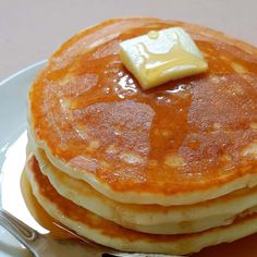 a stack of pancakes with butter on top sitting on a plate next to a fork