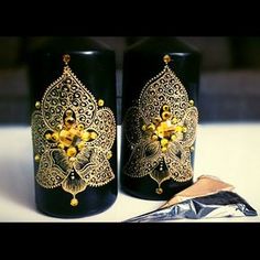 two black vases with gold designs on them sitting next to a piece of tin foil