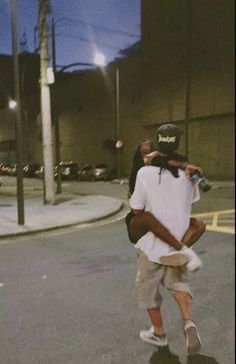 a man walking down the street carrying a woman on his back