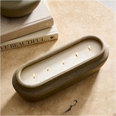 a candle holder with candles in it sitting on a table next to two books and a vase