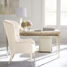 a white chair sitting in front of a desk with a lamp on top of it