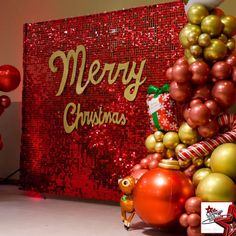 there is a christmas tree made out of balloons and other decorations in front of a merry sign