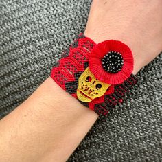 a person wearing a red and black bracelet with a skull on it