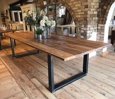 a wooden table sitting on top of a hard wood floor next to a brick wall