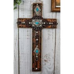 an ornate cross is hanging on the side of a wooden wall next to a potted plant