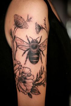 a woman with a bee and flowers tattoo on her arm