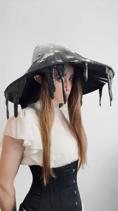 a woman wearing a black and white outfit with dripping chocolate on her head, while standing in front of a gray background