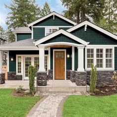 a green house with white trim and wood front door is shown in the suburbs of vancouver, canada