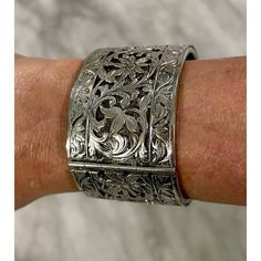 Silver wide pierced bracelet with floral motif. Safety chain and clasp enclosure. Likely silver plate. Signed on clasp. Antique Silver Elegant Bangle, Elegant Metal Cuff Bracelet With Oxidized Finish, Antique Silver Bracelets For Formal Occasions, Elegant Oxidized Metal Cuff Bracelet, Elegant Oxidized Finish Cuff Bracelet For Formal Occasions, Hinged Cuff Bracelet For Formal Occasions, Elegant Silver Cuff Bracelet With Box Clasp, Formal Silver Cuff Bracelet With Sterling Clasp, Vintage Antique Silver Cuff Bracelet