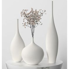 three white vases sitting on top of a marble table