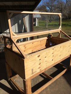 a large wooden box sitting on top of a cement floor next to a building with a chicken cage in it