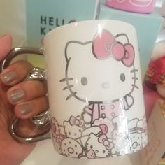 a hello kitty coffee mug is being held by a woman's hand with her nails on it