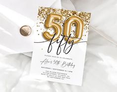 a 50th birthday party with gold balloons and confetti on the table, next to a white envelope