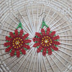 red and green beaded poinsettia earrings on woven wicker basket background