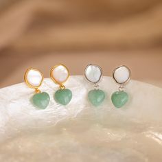 Discover the enchanting beauty of the land and sea with our Jade Heart Drop Earrings ✨ Featuring a lustrous Mother of Pearl and vibrant Jade gemstone, these earrings add a sophisticated pop of color to any look, a must-have for those who appreciate nature-inspired jewelry. SKU: RR-ER542 Product Details Material: High Quality Solid 925 Sterling Silver Finish: 18K Gold ∙ Sterling Silver Featuring dainty Stud Earrings with a ~8mm Mother of Pearl and ~8mm dangling Jade Heart Gemstone Sold as a pair Elegant Heart Shaped Natural Stone Jewelry, Elegant Heart-shaped Natural Stone Jewelry, Elegant Heart-shaped Gemstone Earrings, Round Earrings With Heart Charm As A Gift, Elegant Green Earrings With Heart Charm, Heart-shaped May Birthstone Earrings For Anniversary, Heart Shaped May Birthstone Earrings For Anniversary, Elegant Green Heart Earrings For Gift, Valentine's Day Gemstone Earrings Gift