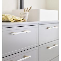 the drawers in this room are painted gray and have brass pulls on them to hold pens