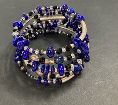 Handcrafted by one of our local artists this memory wrap bracelet is made with blue lapis , Swarovski crystals (which at times reflect a baby blue color), faceted onyx, sterling silver tube beads, and others. It is a one-of-a-kind harmonious fusion.  Blue lapis gemstone is sometimes referred to as "the wisdom keeper", and represents serenity and truth. - Gemstone : Blue Lapis, Faceted Onyx - Metal : Sterling Silver Tube Beads - Bracelet Wrap: 6 - Bracelet Wrist Size: Small Hand Wrapped Blue Beaded Bangle Bracelet, Elegant Blue Stackable Crystal Bracelet, Adjustable Blue Stackable Wrap Bracelet, Blue Crystal Bracelet With Stackable Round Beads, Adjustable Blue Multi-strand Wrap Bracelet, Adjustable Multi-strand Blue Wrap Bracelet, Unique Blue Beaded Bangle Bracelets, Blue Stackable Wrap Bracelet As Gift, Blue Spiritual Stackable Jewelry