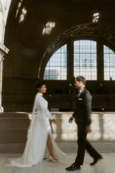 a man and woman are walking in the train station together, dressed in formal attire