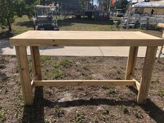 a wooden table sitting on top of a grass covered field next to a parking lot