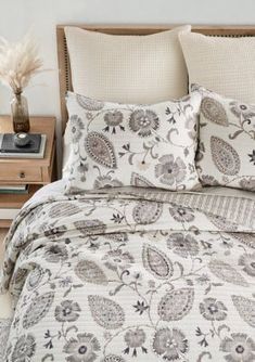 a bed with white and grey comforter in a bedroom next to a night stand