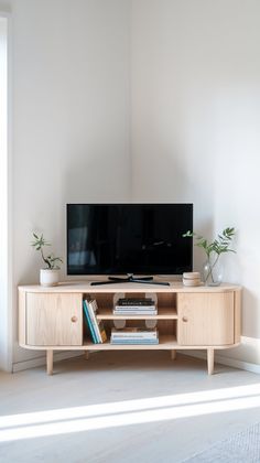 a flat screen tv sitting on top of a wooden entertainment center next to a window