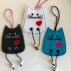 three handmade cat ornament hanging from string