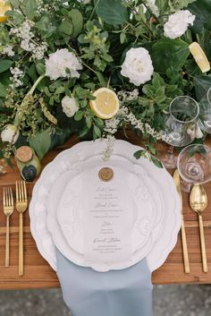 a table setting with plates, silverware and lemon wedges on the place settings