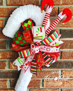 a christmas wreath with stockings and candy canes hanging on a brick wall in front of a door