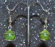 "These jade wrapped bead earrings are made from 10 mm nephrite jade beads and sterling round wire with sterling ear wires. They dangle just enough to be a little dressy but are still appropriate for day wear. Jade is a name given to two different types of stone, nephite and jadeite. The jade I use is nephrite, an amphibole mineral species of tremolite-ferroactinolite. The green is due to iron. Black spot inclusions of magnesite are often visible. My jade comes from British Columbia, Canada and i Green Hand Wrapped Earrings As Gift, Green Hand Wrapped Earrings For Gift, Hand Wrapped Green Earrings For Gifts, Hand Wrapped Round Beads Earrings As Gift, Wire Wrapped Jade Earrings As Gift, Jade Wire Wrapped Earrings For Gifts, Adjustable Wire Wrapped Jade Earrings, Adjustable Round Beads Jade Earrings, Green Jade Dangle Beaded Earrings