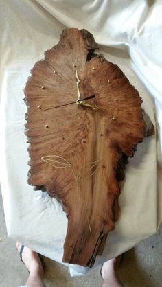 a person standing next to a clock made out of a piece of wood with nails on it