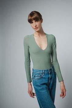 a woman wearing jeans and a green shirt