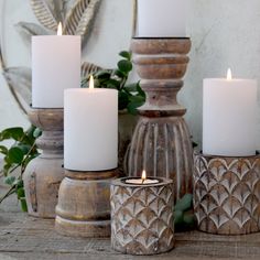 four white candles sitting on top of a wooden table