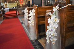 white flowers are tied to pews at a church wedding ceremony, with red carpet