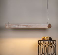 a light hanging over a table next to a vase with some fruit on it,