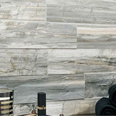 a bathroom with black and gold accessories on the counter top next to a white tiled wall