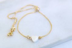 "This beautiful bracelet features a tiny Mother of pearl carved heart on a dainty 18k gold filled chain. A lovely bracelet that you can wear anywhere and with any outfit. It also makes a perfect gift for bridesmaid, best friends or just for yourself. BRACELET SIZE A perfect adjustable chain bracelet. Easy to put on, just slide the gold bead for best fit. 9\" long (Fits most wrist) GEMSTONE * Mother of pearl carved heart * Heart measures approx. 6 mm * Due to the one-of-a-kind nature of the stone Adjustable Heart Pendant Charm Bracelet Gift, Adjustable Heart Bracelet With Delicate Chain For Valentine's Day, Gold Charm Bracelet With Adjustable Length As Gift, Gold Charm Bracelet With Adjustable Length, Adjustable Gold Dainty Heart Bracelet, Adjustable Delicate Heart Bracelet, Adjustable Gold Plated Heart Bracelet For Everyday, Delicate Heart-shaped Bracelets With Adjustable Chain, Minimalist Heart Bracelet With Adjustable Chain As Gift