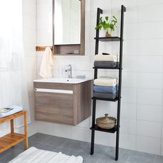 a bathroom with white tile and wooden shelving next to a sink, mirror and towel rack