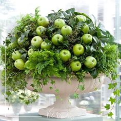 a planter filled with green apples and greenery