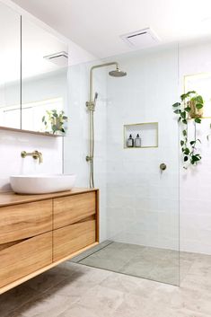 a bathroom with a sink, mirror and shower head in the corner next to a wooden cabinet