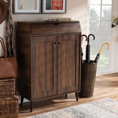 a wooden cabinet with two umbrellas in it and a basket on the floor next to it