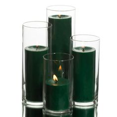 three green candles are sitting next to each other in glass vases on a white background