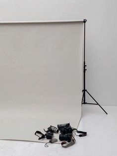 a white backdrop with black shoes on the floor and a camera set up behind it