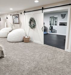 a bedroom with two white bean bags on the floor and an open door leading to another room