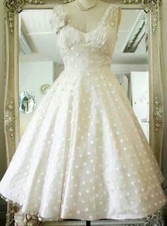 a white dress is on display in front of a mirror with flowers and pearls around it