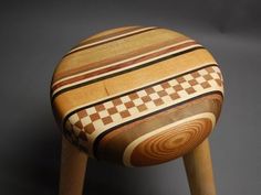 a small stool made out of wood with checkered pattern on it's seat