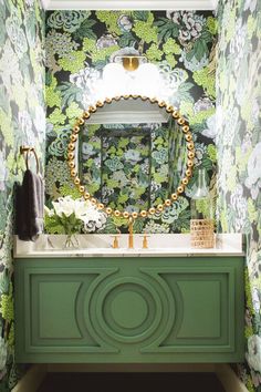 a bathroom with green vanity and floral wallpaper