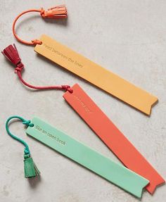 three different colored bookmarks with tassels on each one and an orange string attached to them