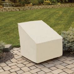 a large white box sitting on top of a brick walkway next to a lush green field